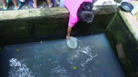 Hondureña recogiendo agua de una pila | Fotografía de archivo