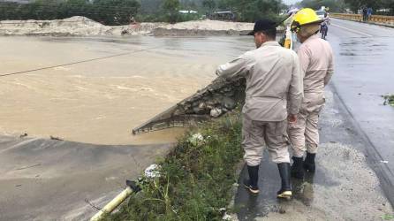 Dos bomberos supervisan los daños provocados por lluvias en Omoa, Cortés.