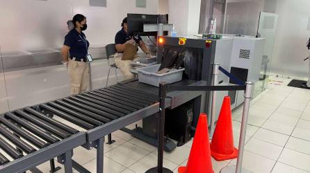El personal del Departamento de Seguridad Aeroportuaria revisa el equipaje de una persona con una máquina de rayos X.