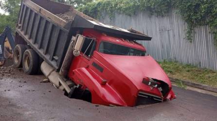 Volqueta roja dentro de un socavón en Lomas del Guijarro, Tegucigalpa.