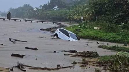 Uno de los dos carros que fueron arrastrados por las aguas que han dejado las lluvias en Roatán, Islas de la Bahía.