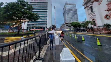 Dos mujeres se cubren de la lluvia en el centro de San Pedro Sula.