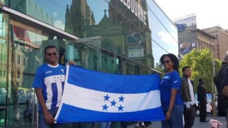 Néstor Güity y su esposa Behannis, originaria de República Dominicana, posan con la Bandera Nacional de Honduras.