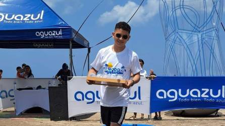 Un competidor porta una bandeja de botellas de Aguazul mientras camina con aletas de buceo, llamadas también pataletas, entre botellones de agua. El reto es no dejar caer las botellas de agua.