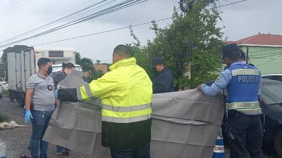 Policías cubriendo el cuerpo de la víctima.