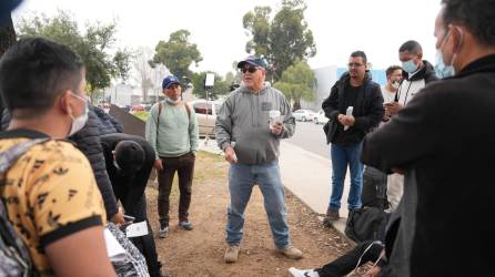 Robert Vivar (c), de la Iglesia Episcopal de San Diego, habla con un grupo de migrantes liberados por la Patrulla Fronteriza este lunes, en San Diego, California.