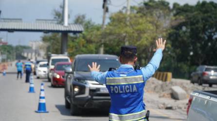 Un agente de la Policía realiza la señal de detenerse a un conductor de una camioneta en el bulevar del este de San Pedro Sula.