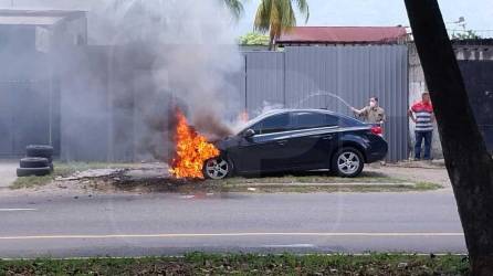 Un vecino lanza agua al carro en llamas.