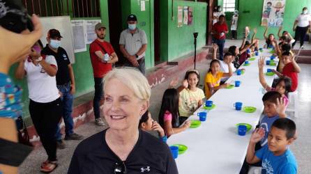 La embajadora de Estados Unidos ante las agencias de la Organización de las Naciones Unidas (ONU) en Roma, Cindy H. McCain, sonríe junto a los niños que comen su merienda.
