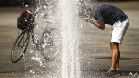 Ciudadano se refresca en medio de la calle | Fotografía de archivo