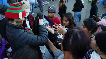 Voluntarios entregan regalos a migrantes centroamericanos en las afueras de un albergue en Tijuana.