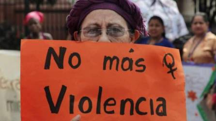 Una mujeres sostiene una cartulina color naranja con la leyenda “No más violencia”.