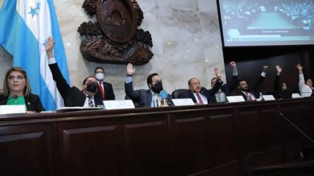 Diputados del Congreso Nacional de Honduras levantan su mano para votar.