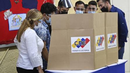 Autoridades y técnicos revisan una máquina de votación en un colegio electoral durante las elecciones regionales y municipales en Fuerte Tiuna en Caracas.