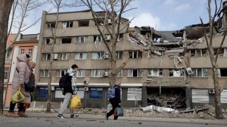 Personas caminando frente a un edificio dañado en la ciudad ucraniana de Mykolaiv.
