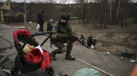 Un militar ucraniano se pone a cubierto mientras la gente evacúa la ciudad de Irpin.