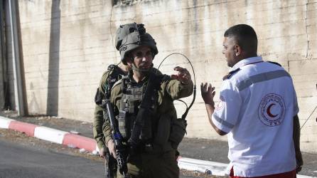 Un soldado habla con un médico de la Media Luna Roja cerca del área donde tres palestinos murieron por disparos del Ejército israelí cerca de la ciudad cisjordana de Nablus, el 25 de julio de 2023