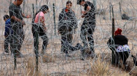 Migrantes intentan cruzar la cerca de alambres en la frontera que divide a México de los Estados Unidos.