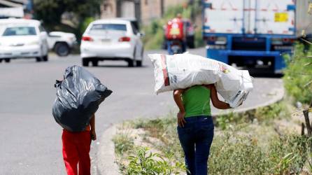 Dos niños cargan bolsas donde llevan botes plásticos para reciclar en Olancho (Honduras).