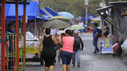Mujeres se protegen de la lluvia con un paraguas en San Pedro Sula, Honduras. | Fotografía de archivo