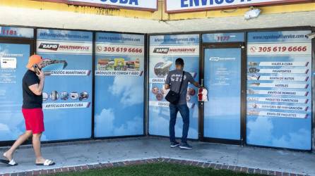 Dos personas frente a una agencia de viajes y servicios de carga a Cuba, en Hialeah, Florida.