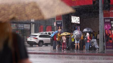 Personas tratan de refugiarse de la lluvia a lo largo de Hollywood Boulevard cuando la tormenta tropical Hilary llega a Los Ángeles, California.