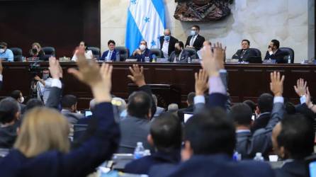 Diputados de Honduras levantan su mano para votar en sesión del Congreso Nacional.