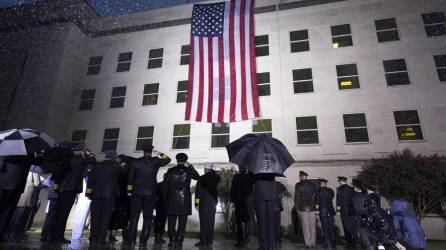 Supervivientes y miembros del Ejército escuchan el himno nacional junto a una bandera desplegada en el Pentágono, en Arlington, Virginia, Estados Unidos este domingo durante el 21º aniversario del atentado a las Torres Gemelas y el Pentágono del 11-S.