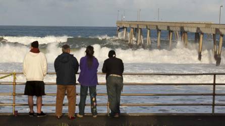 Varias personas observando las olas en Pacífica, California.