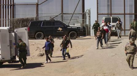 Migrantes detenidos son llevados hoy por miembros de la Patrulla Fronteriza estadounidense a un vehículo, junto al muro fronterizo en El Paso, Texas (EE.UU).