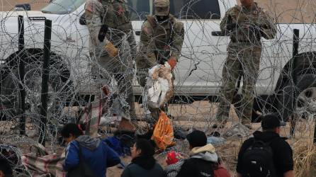 Soldados estadounidenses esperan tras una alambrada de navajas y púas mientras migrantes intentan pasar a Texas desde Ciudad Juárez (México).