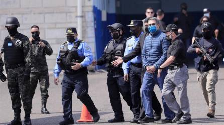 El expresidente hondureño Juan Orlando Hernández (c) es dirigido a la aeronave que lo llevará extraditado a los Estados Unidos.