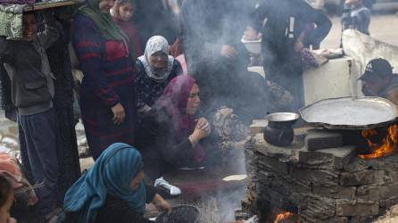 Familias palestinas desplazadas hacen pan en un horno de leña debido a la ausencia de gas en un campo de refugiados en Rafah, en las Franja de Gaza, este sábado. EFE/ Haitham Imad
