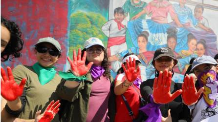 Manifestantes muestran sus manos pintadas de rojo durante una movilización con motivo del Día Internacional de la Mujer este viernes, en Tegucigalpa (Honduras). EFE/ Gustavo Amador