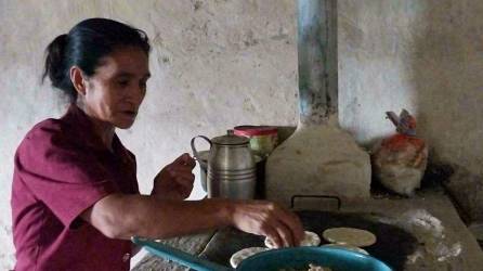 María Isidra López Martínez (49 años) muele y refina en piedra el maíz para luego echar las tortillas y acompañar el almuerzo-cena con pollo y frijolitos.