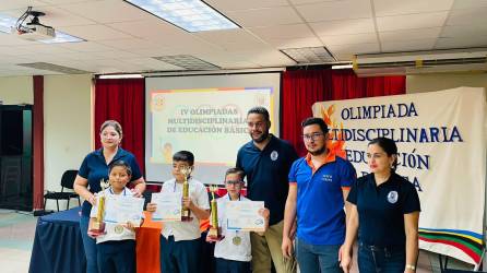 Los alumnos de la escuela Hogar San José, Ángel Fernández, Kennet Lenin Villanueva y Anthony Martínez reciben el trofeo de primer lugar de las Olimpiadas Multidisciplinarias.