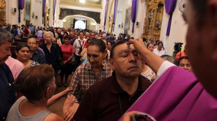 Un sacerdote pone una cruz en la frente de un feligrés en el Miércoles de Ceniza.