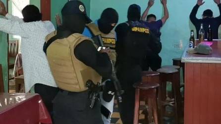 Agentes de la Dirección Policial Anti Maras y Pandillas Contra el Crimen Organizado (DIPAMPCO) revisan a unos hombres en un negocio de bebidas alcohólicas.