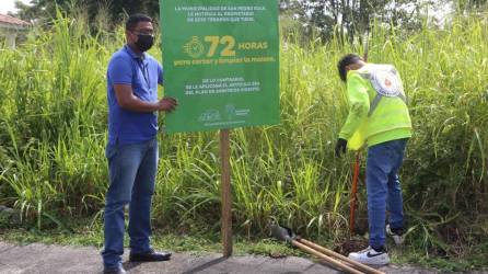 Empleados municipales colocan un rótulo en un solar baldío.