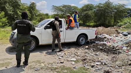 Policías municipales inspeccionan a hombres que tiran basura.