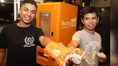 Dos chicos muestran burritos comprados del Burrito Box.
