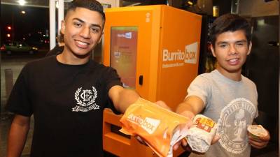Dos chicos muestran burritos comprados del Burrito Box.