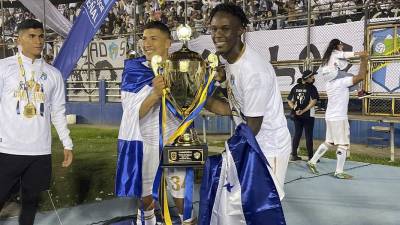 Román Rubilio Castillo y Kevin López, enfundados con la bandera de Honduras, posando con el trofeo de campeones del fútbol de Guatemala.