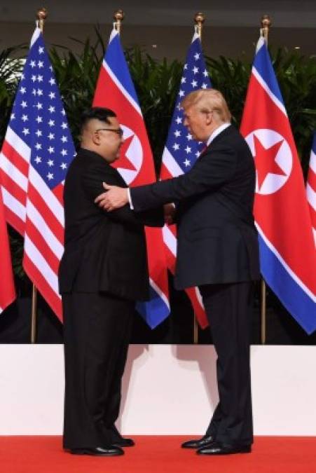 North Korea's leader Kim Jong Un (L) shakes hands with US President Donald Trump (R) at the start of their historic US-North Korea summit, at the Capella Hotel on Sentosa island in Singapore on June 12, 2018.<br/>Donald Trump and Kim Jong Un have become on June 12 the first sitting US and North Korean leaders to meet, shake hands and negotiate to end a decades-old nuclear stand-off. / AFP PHOTO / SAUL LOEB