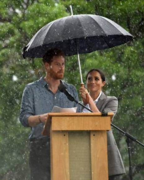 La lluvia comenzó mientras Harry pronunciaba un discurso en una barbacoa comunitaria, los transeúntes le ofrecieron un paraguas, pero Meghan ya había protegido a su marido.<br/>