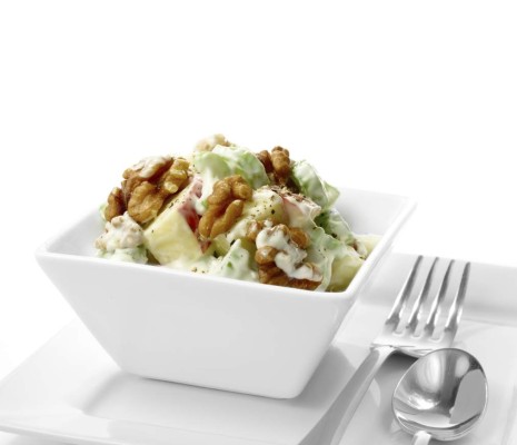 Studio macro of fresh Waldorf Salad with black pepper, walnuts, apple and celery against a white background. A perfect image for your restaurant showing attention to detail. Copy space.