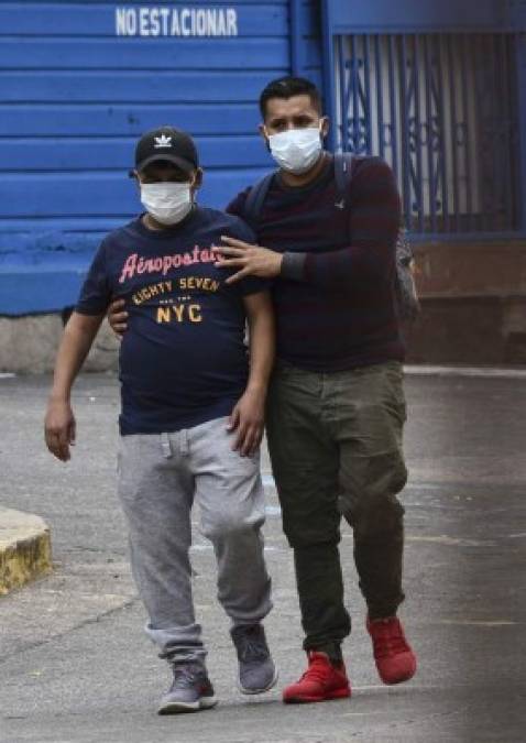 Un paciente con COVID-19 es ayudado por un hombre en un hospital de campaña establecido en el patio del Hospital Escuela. AFP