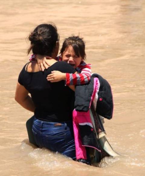 Los niños se aferran a sus padres con pánico al cruzar el caudaloso río.