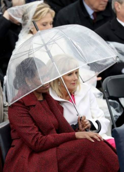 Michelle Obama y Jill Biden se protegen de la lluvia.