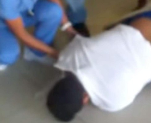 Una enfermera trata de ayudar al paciente tirado en el piso pero este no lo permite. Foto YouTube.